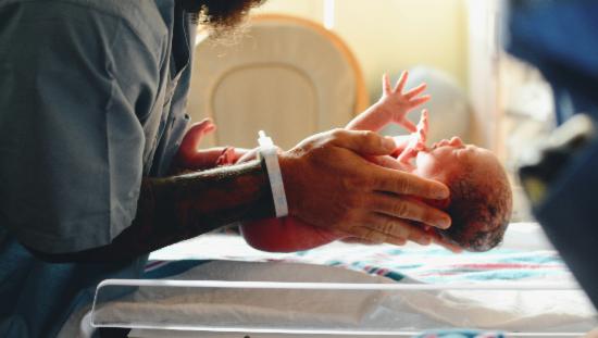 Nyfødt baby blir holdt av sykepleier