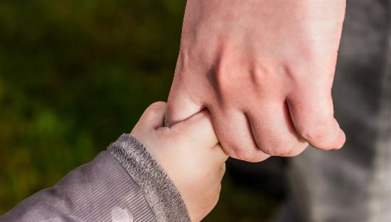 Barnehånd som holder i en større hånd