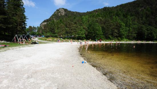 Bildet viser strand med mange som bader i bakgrunnen.